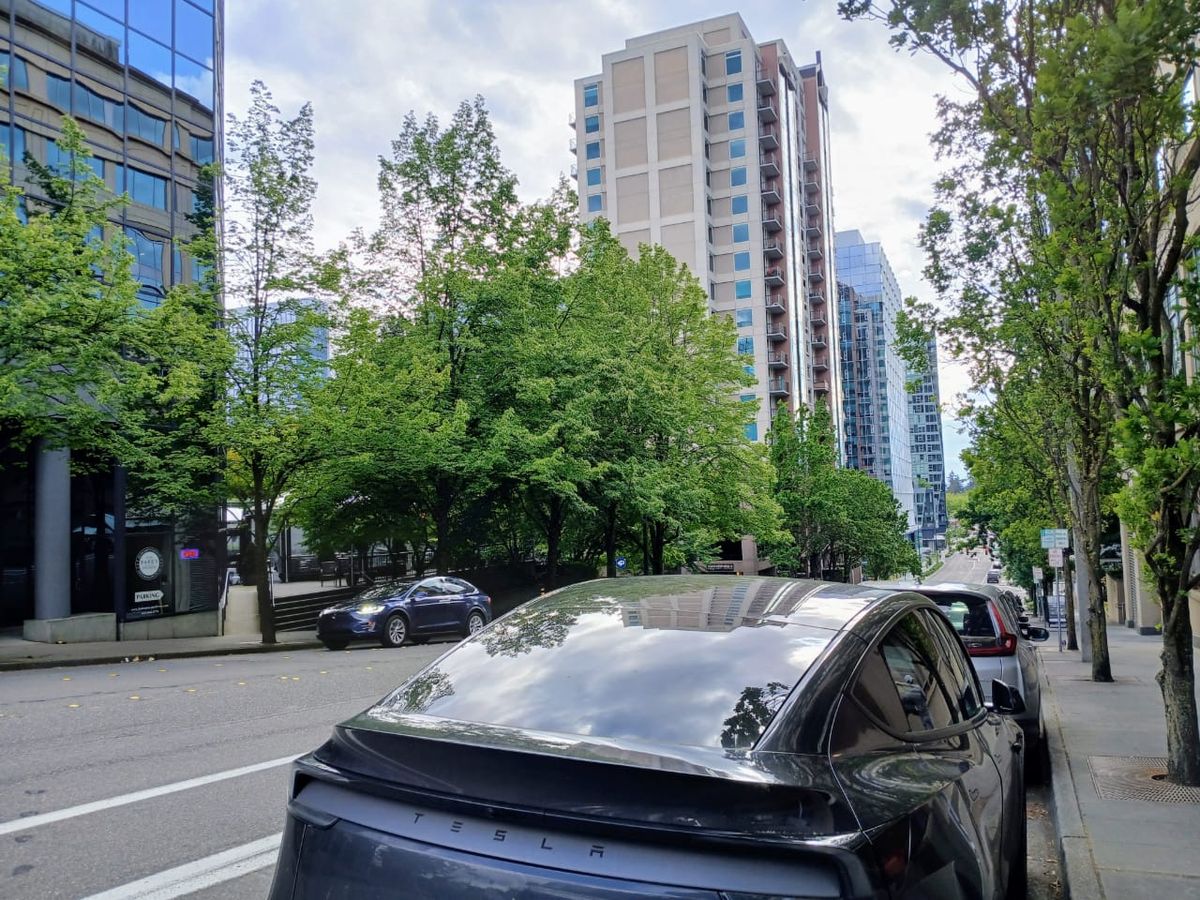 A street in downtown Bellevue with parked cars along the curb adjacent to retail establishments.