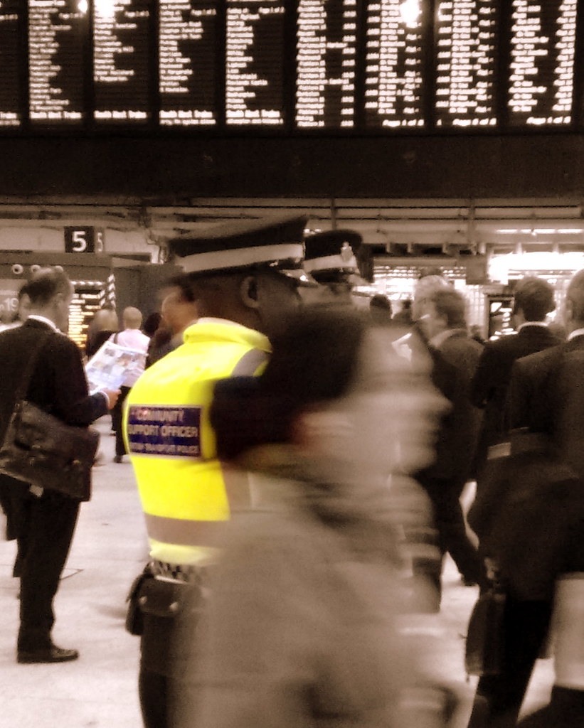 A busy London Underground station platform with trains arriving and departing.