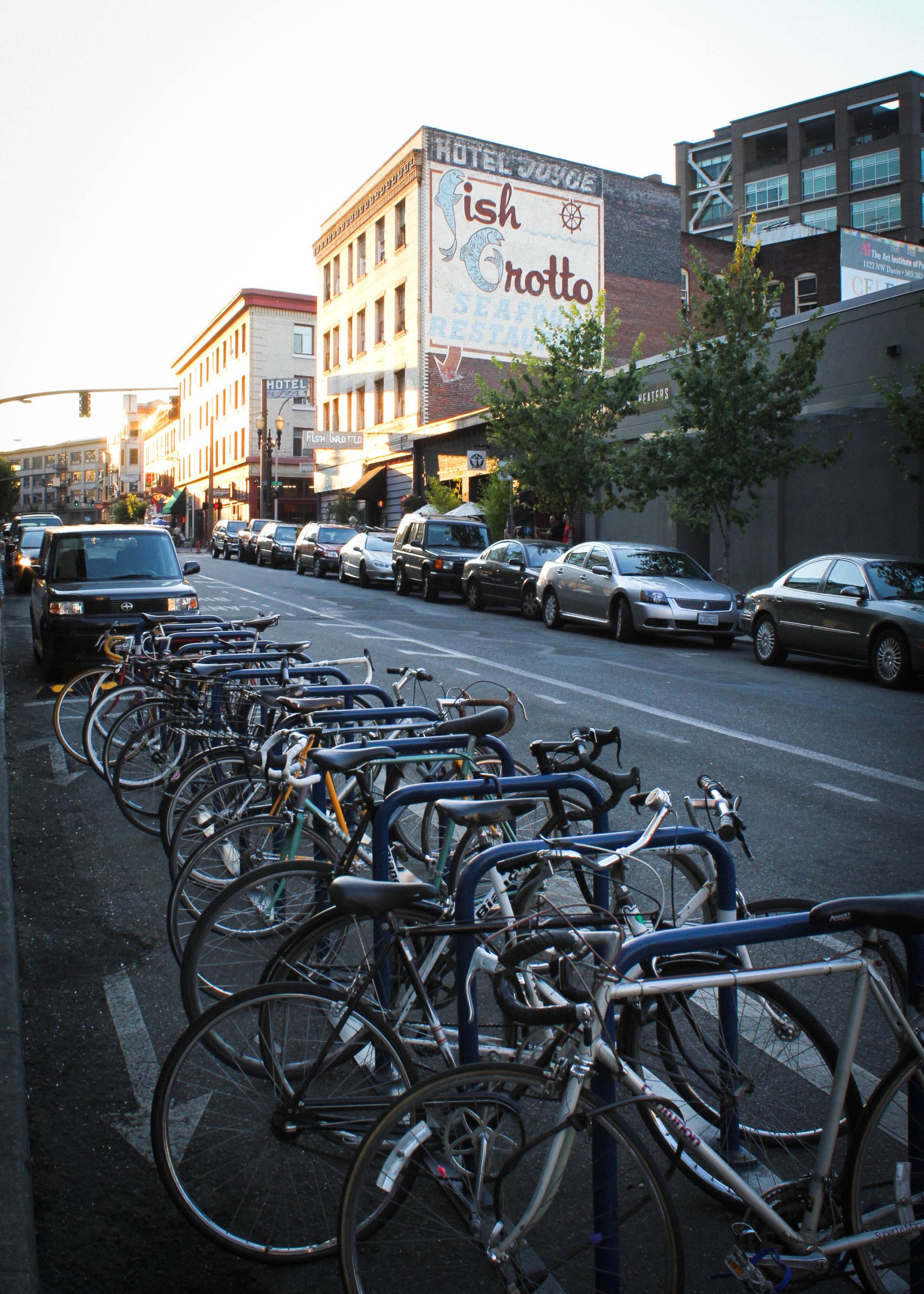 A row of shared bicycles parked on a street in Portland, Oregon, with city buildings in the background.