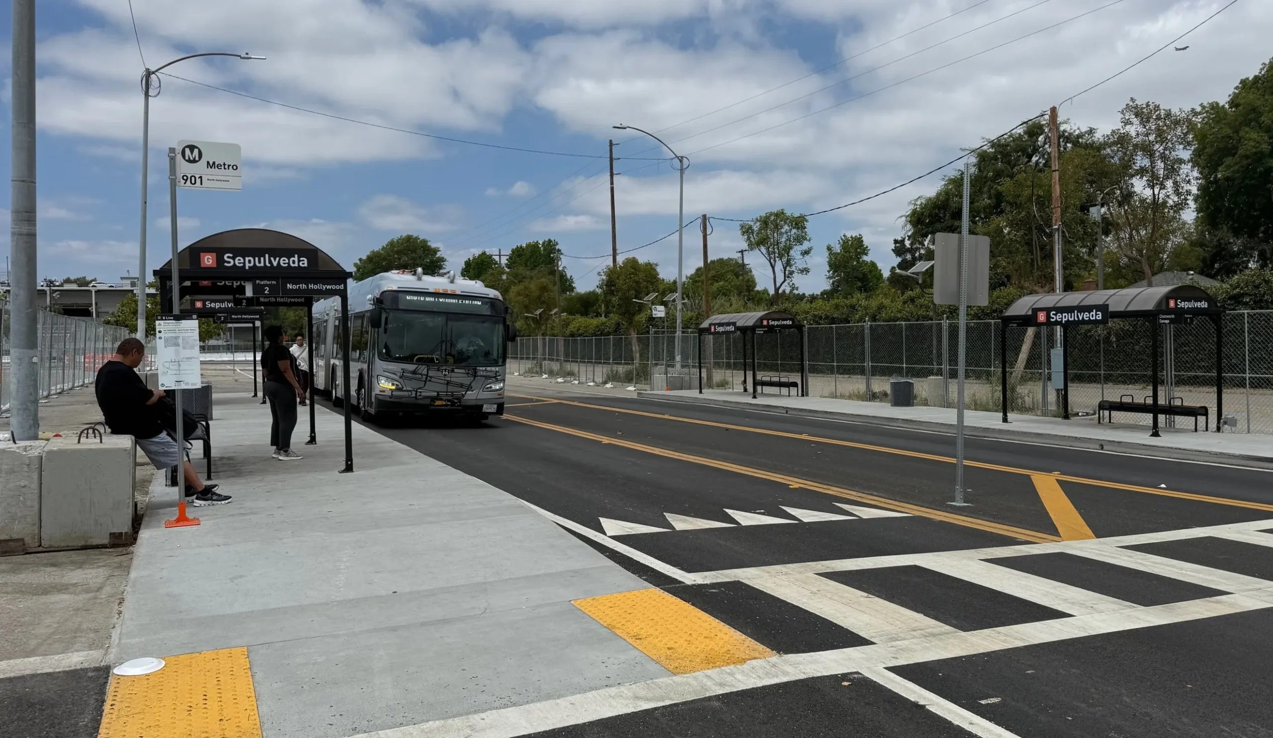A bustling Los Angeles Metro bus and train station with passengers and signage.