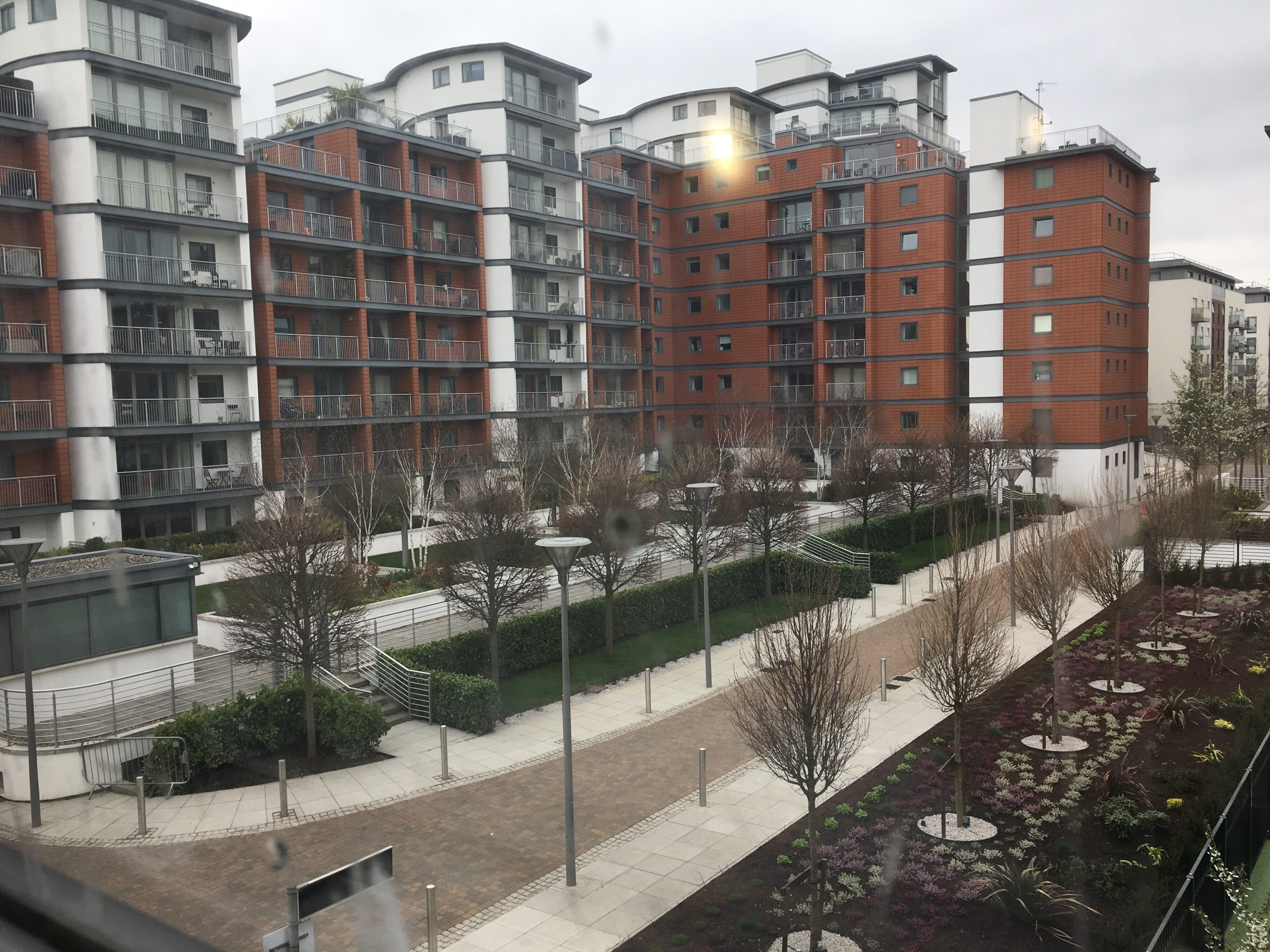 A modern residential street in London with mixed-use buildings and construction in the background.