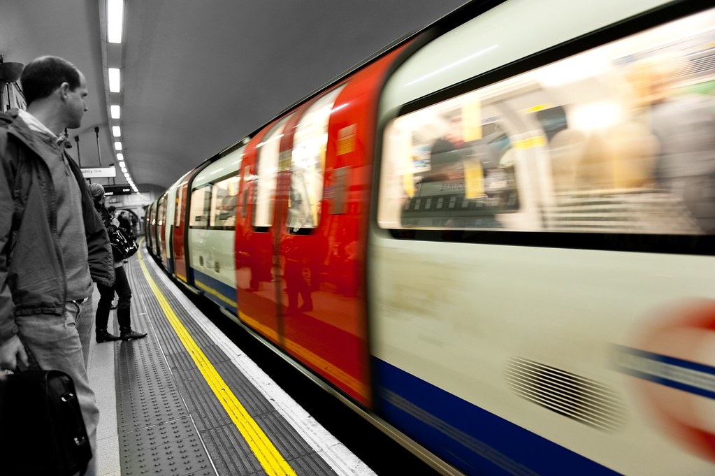 A bustling London Underground station with trains arriving and departing, illustrating the scale of Transport for London's network.