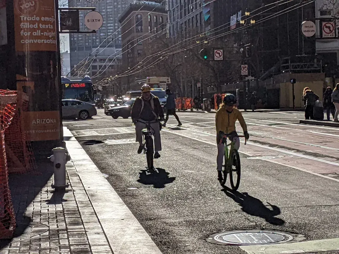Cyclists navigating a street in San Francisco, with visible street signage and urban infrastructure.