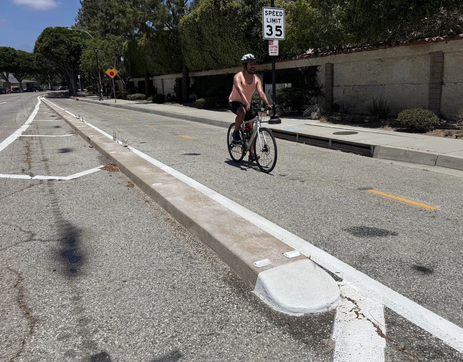 Cyclists using a protected bikeway with concrete curbs on Elenda Street in Culver City.