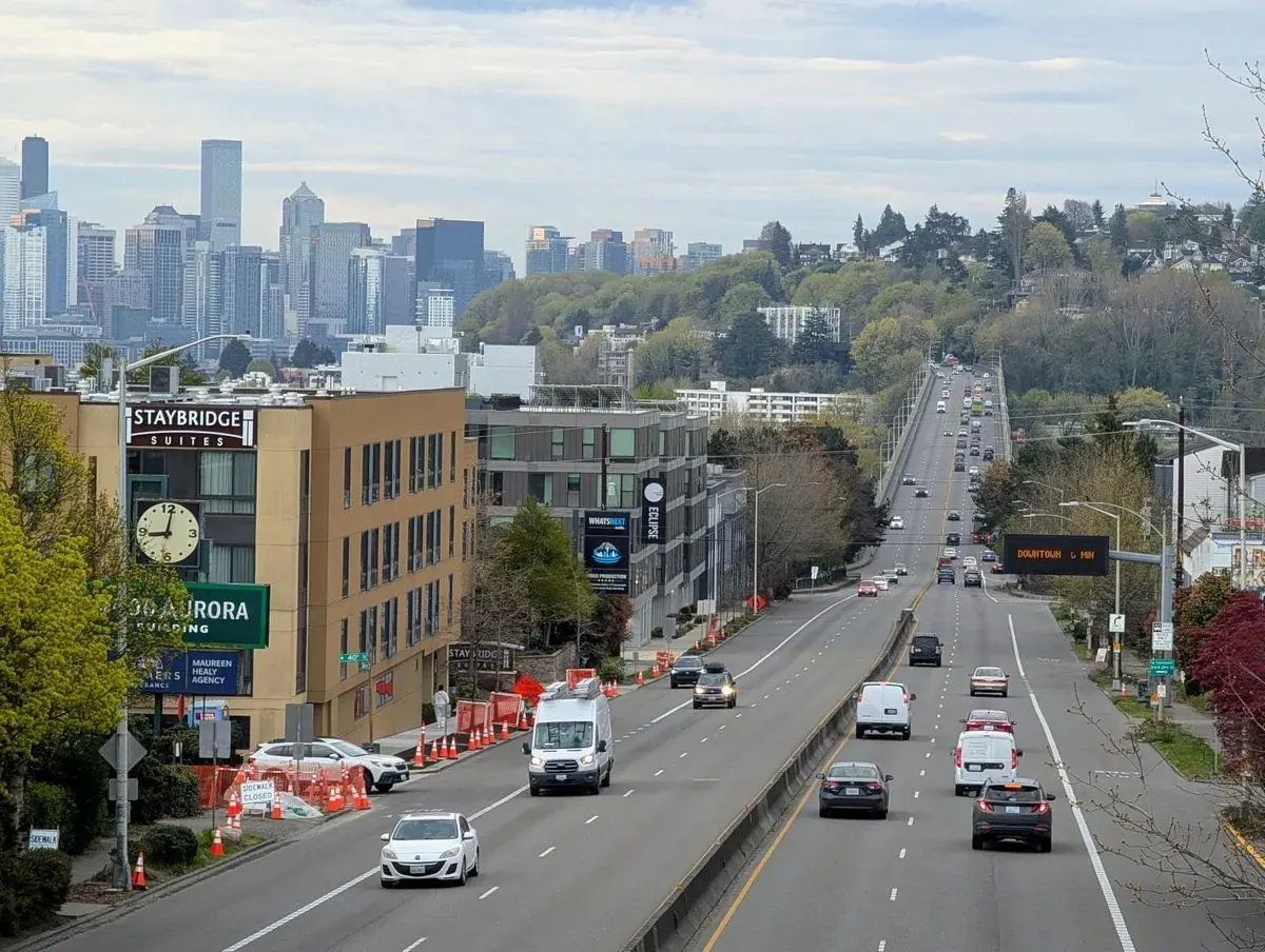 Seattle skyline viewed from a distance, showing urban development with cranes indicating ongoing construction.
