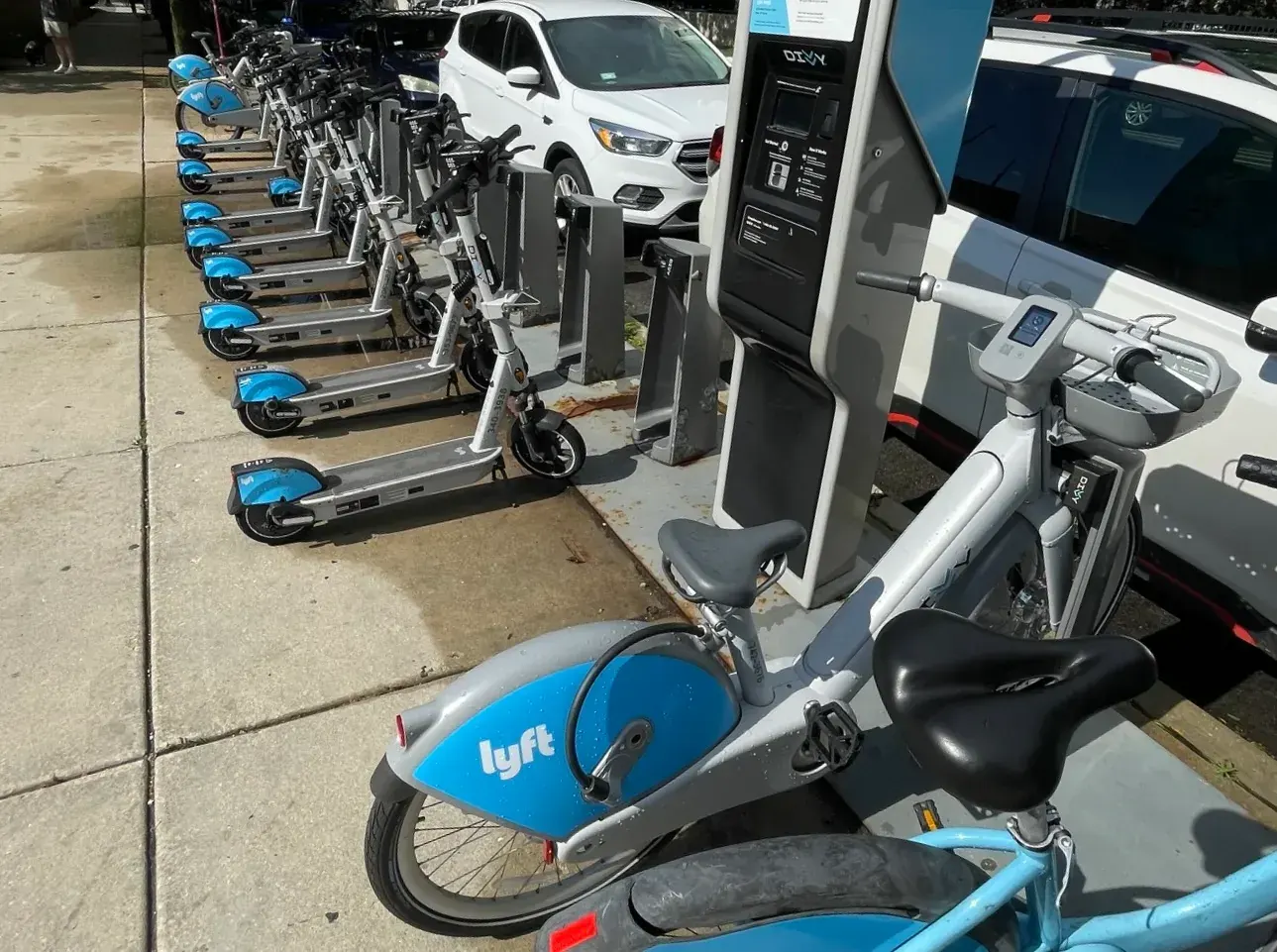 A street scene in Chicago featuring multiple Divvy bike share stations, some occupied by electric bikes.