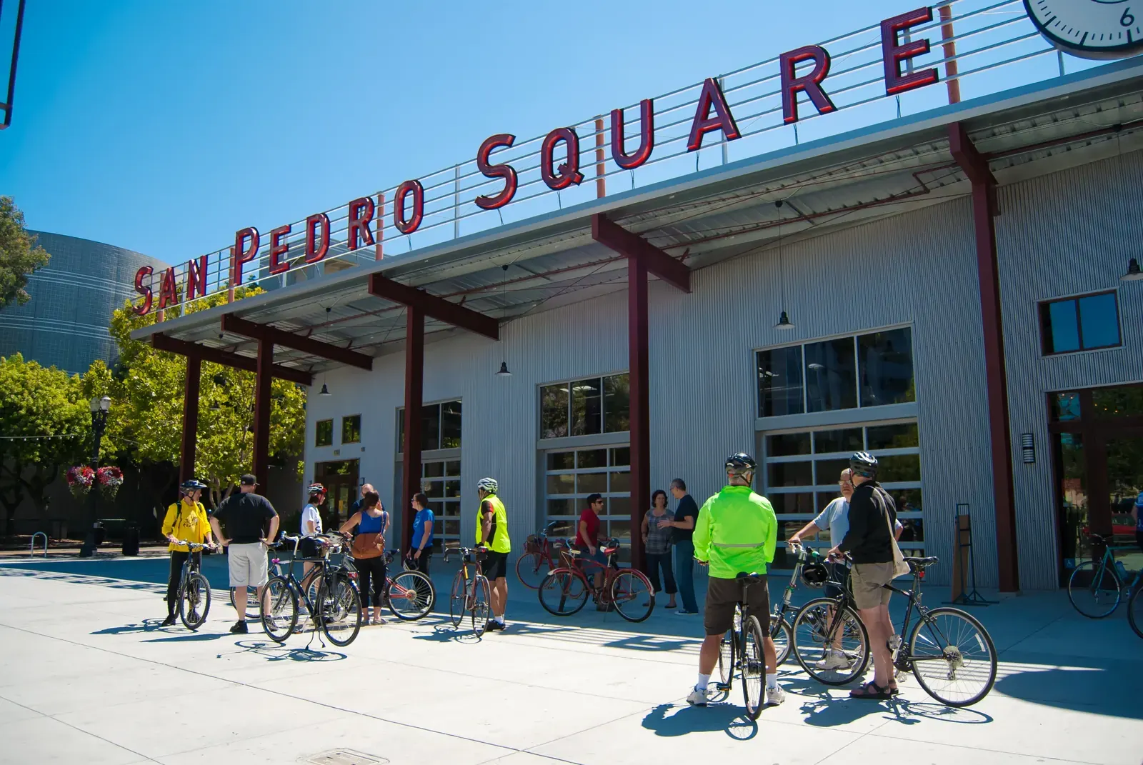 A lively street scene on San Pedro Street in San Jose, featuring outdoor dining, public art, and people enjoying an event.