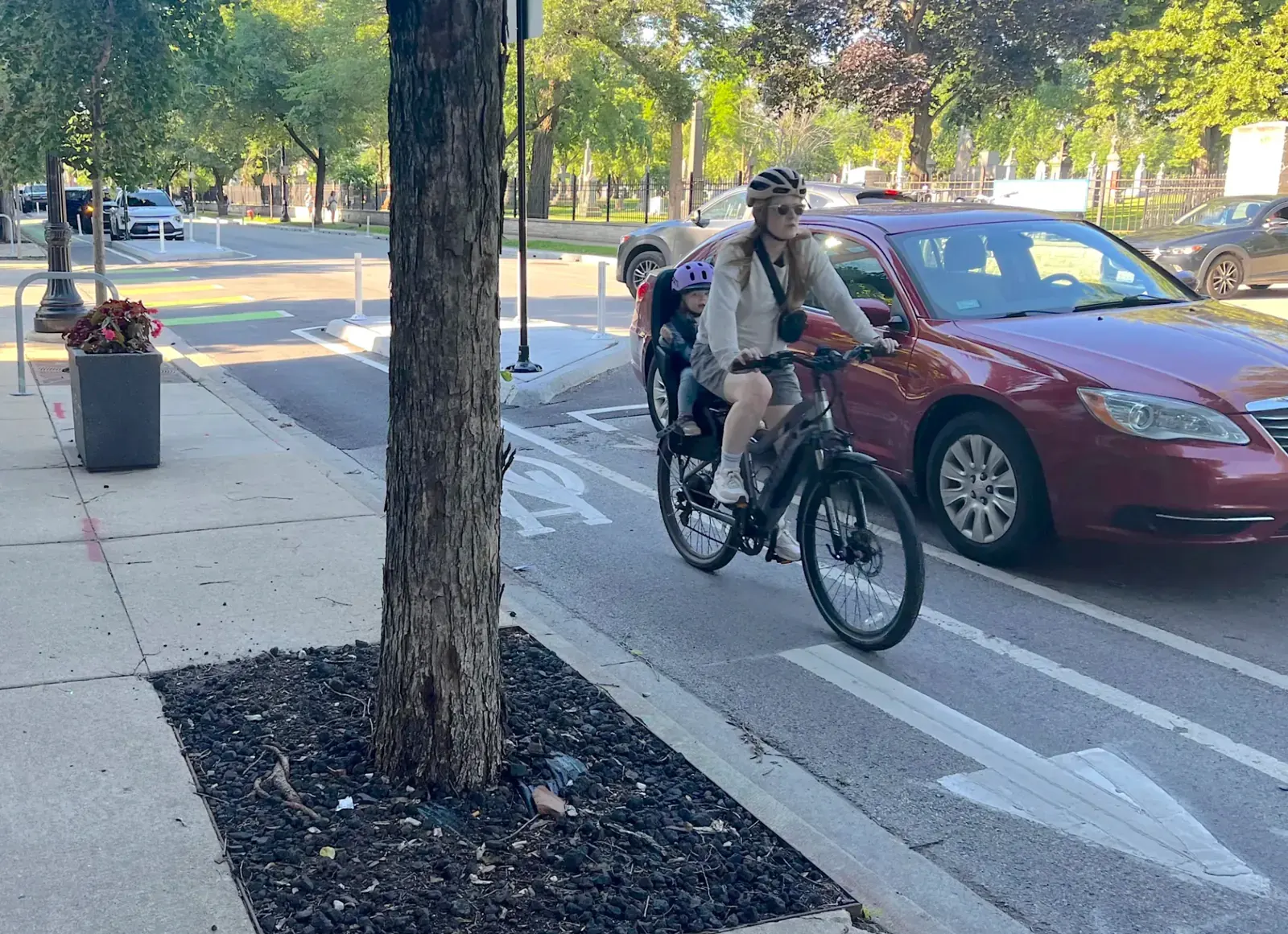 A cyclist navigating a city street with traffic and buildings in the background.