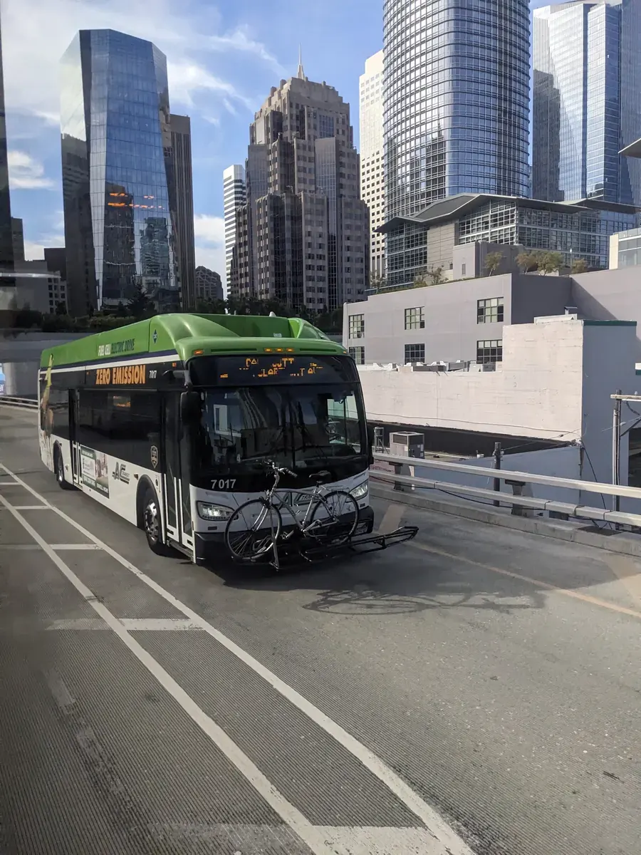 A San Francisco Municipal Transportation Agency (SFMTA) bus and a Muni Metro light rail train operating on city streets.