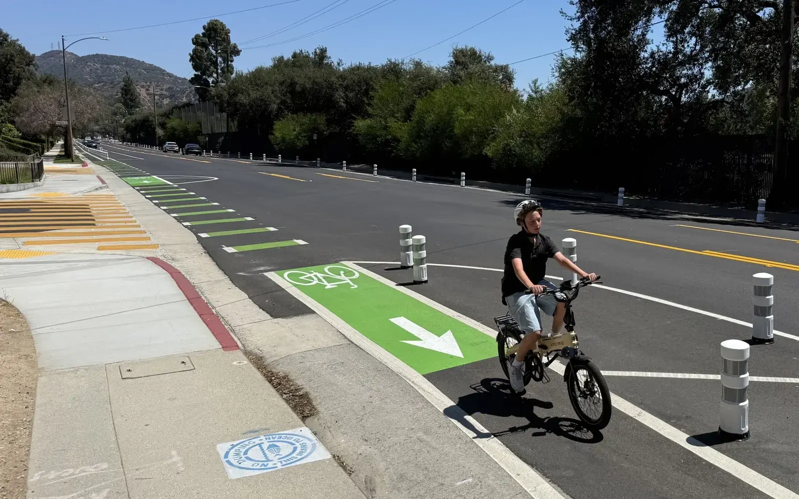 A street view of La Crescenta Avenue in Glendale, California, showing ongoing construction and newly painted bright green bicycle lanes.