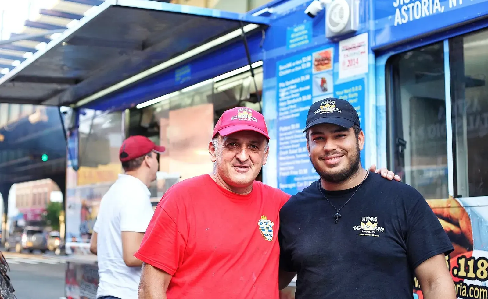 The King Souvlaki food truck parked beside a protected bike lane on 31st Street in Astoria, Queens, with a sign reading "Slow down and grab a gyro!" for cyclists.
