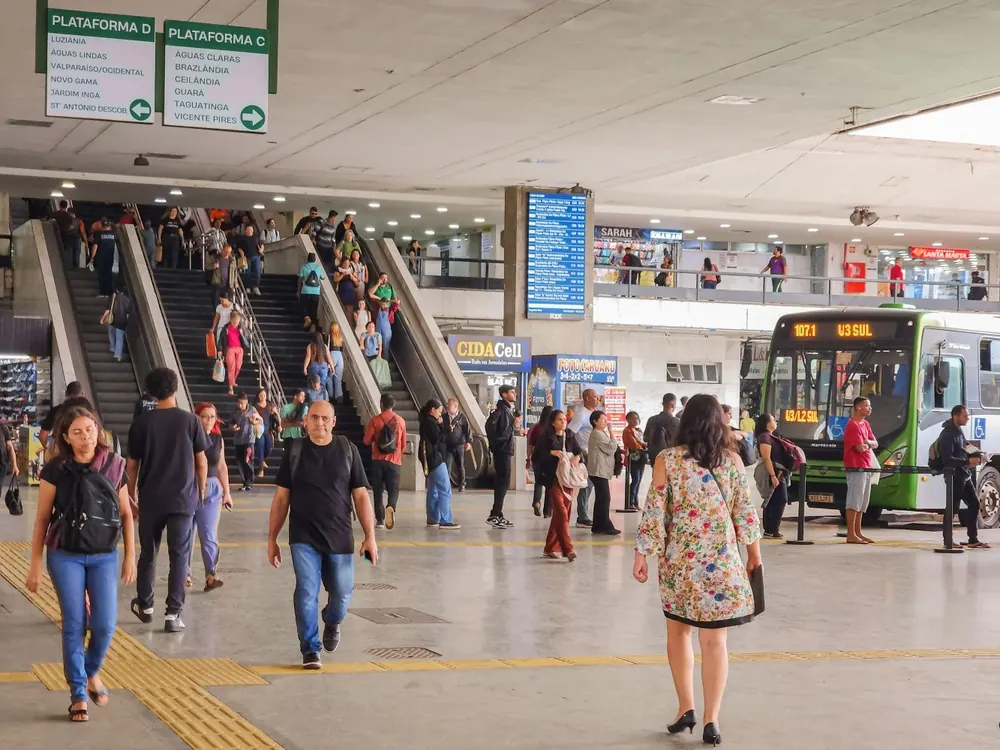 A busy street in a Brazilian city showcasing various modes of public transportation alongside pedestrian and cycling infrastructure.