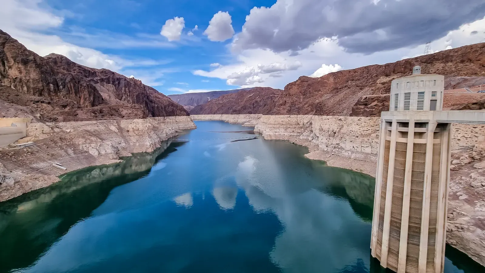 Lake Mead showing white bathtub ring of mineral deposits on canyon walls, indicating dramatically reduced water levels, with Hoover Dam in background